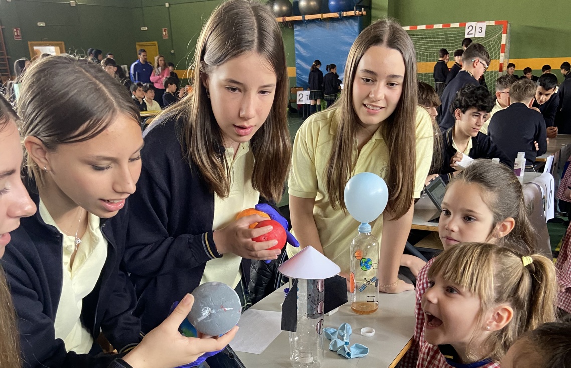 Un grupo de estudiantes acerca su proyecto a las niñas de Infantil.