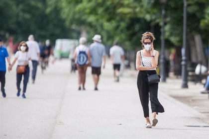 Una mujer habla por teléfono mientras pasea portando la mascarilla obligatoria.