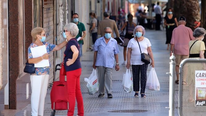 Personas pasean por la calle portando la mascarilla obligatoria.