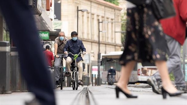Dos personas pasean en bicicleta con mascarilla.