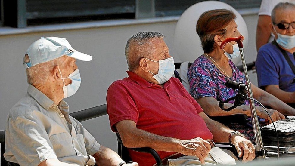Un grupo de ancianos descansa portando la mascarilla obligatoria.
