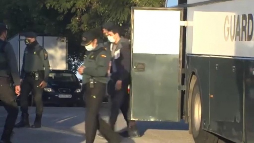 Uno de los individuos detenidos es escoltado por los agentes.