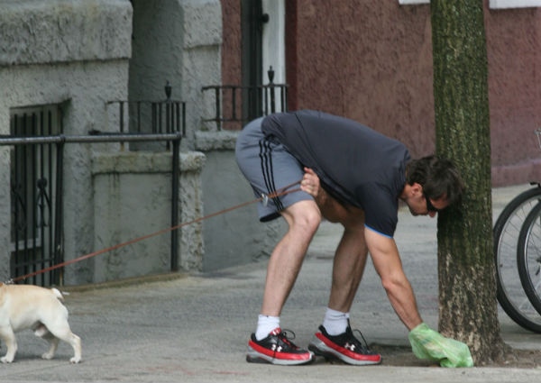 Propietario recogiendo la deyección de su mascota.