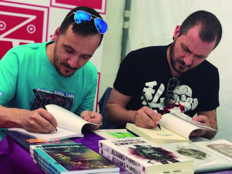El escritor David Ruiz del Portal y el dibujante Juapi firman su libro-juego 'En las garras de Babá Yagá'.